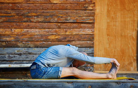 young man doing yoga in the early morning on the garden terrace of the houseの写真素材