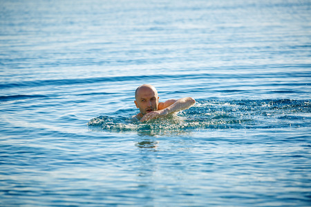 smiling man swims in the sea at dawnの写真素材