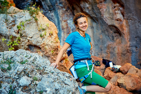 female rock climber stands on a rocky wall backgroundの写真素材
