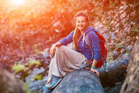 Active healthy woman hiking in beautiful forest. Portrait of happy smiling young woman resting of forest clearing during hike holidays.の写真素材