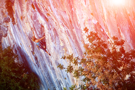 female rock climber climbs on a rocky wallの写真素材