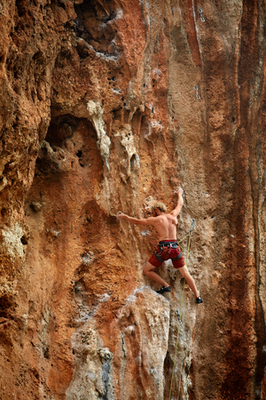 male rock climber climbs on a rocky wallの写真素材