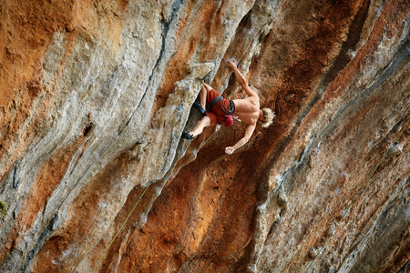 male rock climber climbs on a rocky wallの写真素材