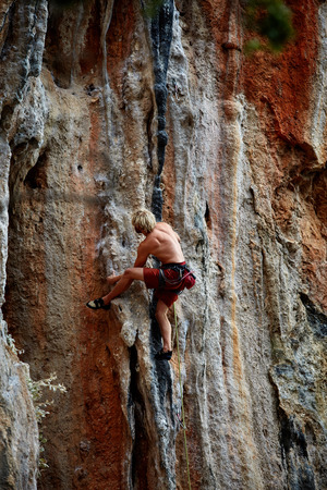 male rock climber climbs on a rocky wallの写真素材