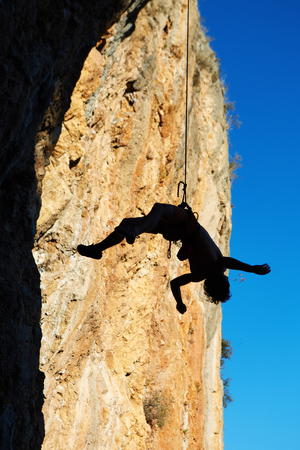 climber hanging on rope, silhouette on the rocks backgroundの写真素材