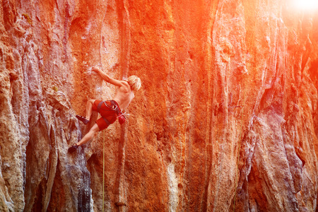 male rock climber climbs on a rocky wallの写真素材