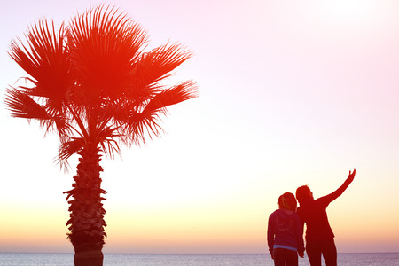 woman's stands on the embankment and prepares for jogging on the beach against sunrise skyの写真素材