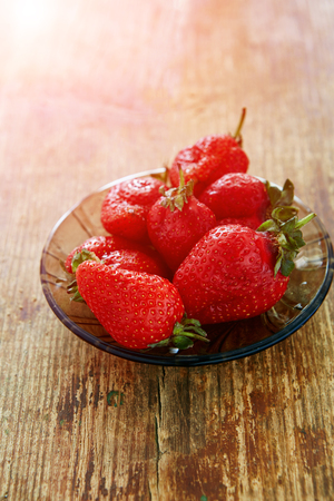 fresh strawberries on a plate on a wooden backgroungの写真素材