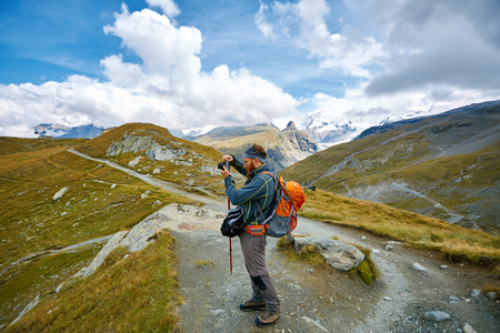 hiker with backpack and camera on the trail in the Apls mountains. Trek near Matterhorn mountの写真素材