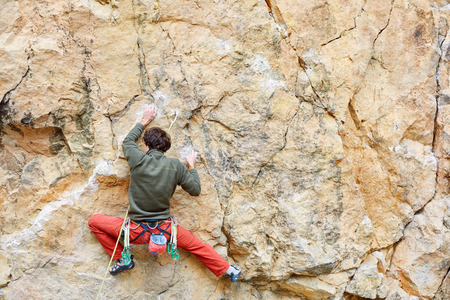 male rock climber climbs on a rocky wallの写真素材