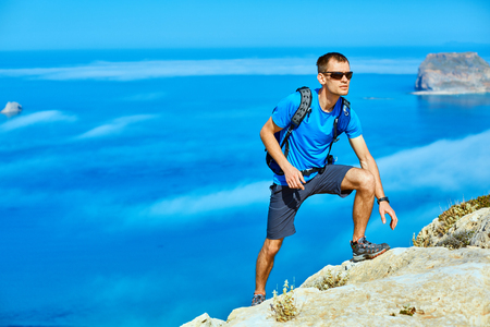man runs on a rock against a  blue seaの写真素材