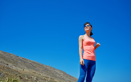 Female on summer or spring leisure vacation raising arms to sky towards the seaの写真素材