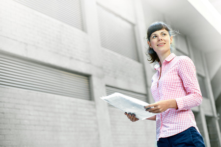 business woman with a folder of papers on a background of gray walls of the building.の写真素材