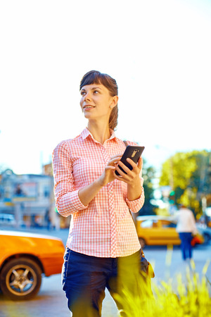 young woman with phone standing outdoor.の写真素材