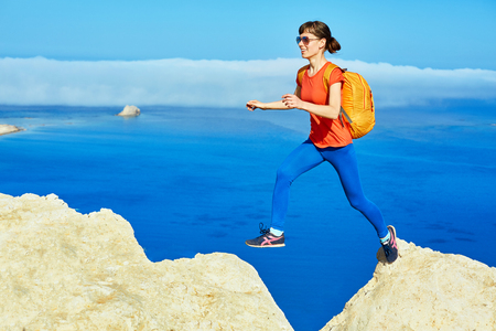 panoramic view on Balos beach, Crete, Greece. Woman, traveller jumping on the cliff against sea backgroundの写真素材