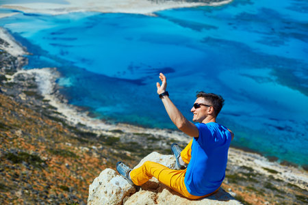 male traveler on the cliff against blue sky and sea
