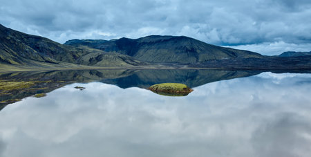 Lake coast with mountain reflection at the cloudy day, Icelandの写真素材