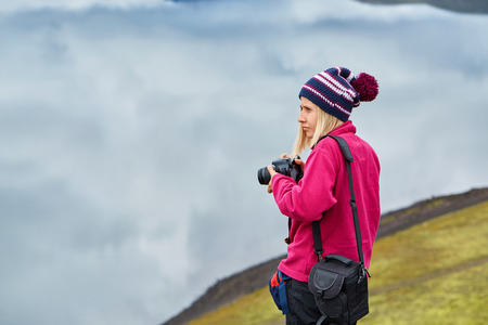 woman hiker photographer taking picture on the lake background in Icelandの写真素材