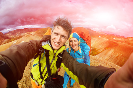 man hiker photographer taking selfie with his girlfriend on the rhyolite mountains background in Icelandの写真素材