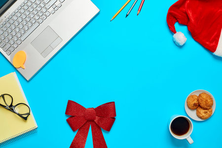 Top View of blue Office Table with cropped Laptop, clips, pencils, notebook with glasses and...