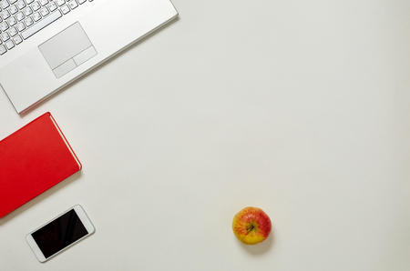 Creative Office Bright Table with laptop Keyboard, apple and smartphone. Top View with Copy Spaceの写真素材
