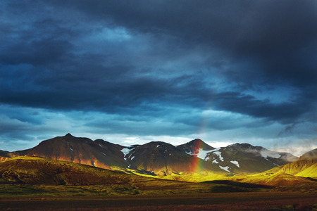 Travel to Iceland. Beautiful sunset in camping near Alftavatn lake. Icelandic landscape with mountains, sky and clouds. Trekking in national park Landmannalaugar. Rainy Evening with big rainbow.の写真素材