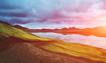 Lake coast with mountain reflection at the cloudy day, Icelandの写真素材