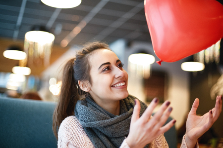 Happy smiling woman with balloon in the form of heart in a cafe. Couple in love on a date. Love story and Valentines Day conceptの写真素材