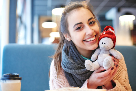 Couple in love on a date. A woman receives a gift from a man. Presented with a teddy bear in a red cap. Love story and Valentines Day conceptの写真素材