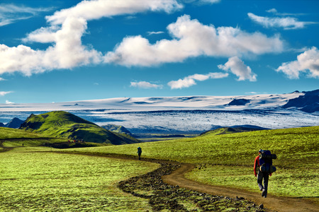 man hiker on the trail in the Islandic mountains. Trek in National Park Landmannalaugar, Iceland. valley is covered with bright green mossの写真素材