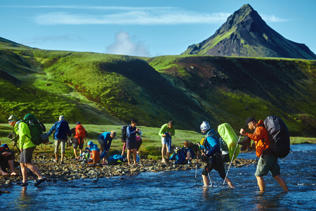 hikers with backpacks on the trail in the mountains. Trek in Iceland. people are moving across the creekの写真素材