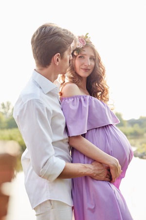Pregnant woman and her husband walks in park at evening. Family enjoying pregnancy. The concept of Mothers Day and Womens Day.の写真素材