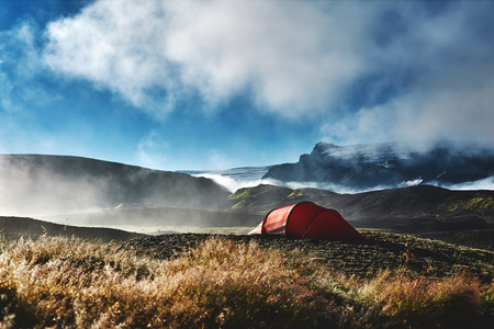 Travel to Iceland. Beautiful Icelandic landscape with mountains, sky and clouds. Trekking in national park Landmannalaugar. Morning in Camping . Tents and hikers in the camping. Travel concept.の写真素材