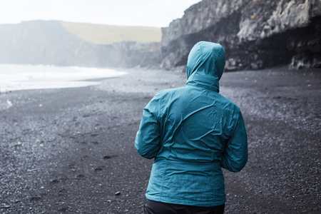 woman walking along the beach in a storm. black sand beaches on the Atlantic coast in Icelandの写真素材