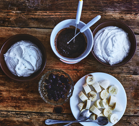 dieting cottage cheese with fresh bananas, Fondue with chocolate on a dark old wooden table. Table setting for two. view from aboveの写真素材