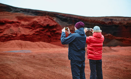 Quarry in a volcano crater in Iceland. Stone rock red and black. Tourist takes pictureの写真素材