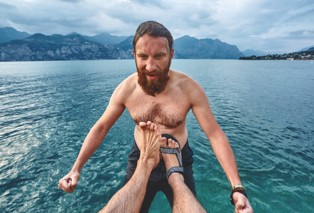 The man is kicked into the water from the pier. Lago di Garda lake, Italyの写真素材