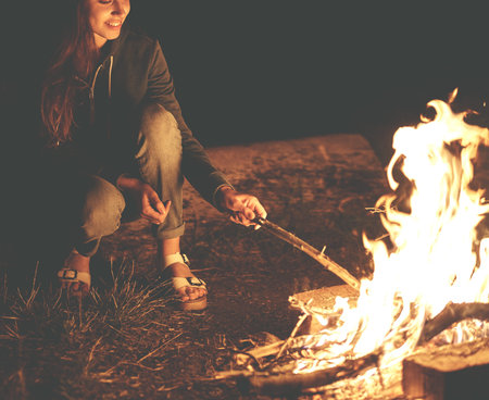 Young woman in geans and hoodie in the mountains. Young woman with fire on mountain at sunset. Girl...