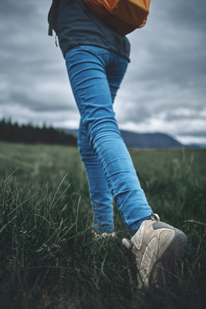 feet of woman hiker hiking in beautiful mountains on the green pines backgroundの写真素材