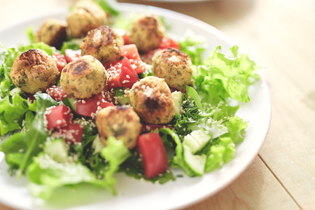 Fried falafel in a cast-iron pan close up. Middle eastern dish falafel pan and dishes with salad on the wooden backgroundの写真素材