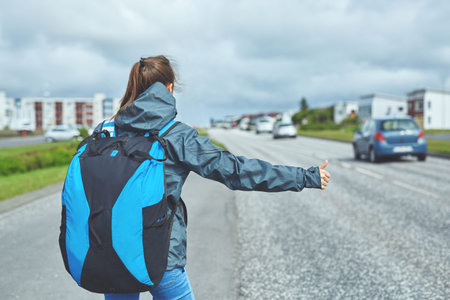 woman traveler with backpack stops the car on the road