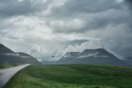 Travel to Iceland. A mountain road with fog to the town of Isafjordur and a view of the fjord after rain. focus on the roadの写真素材