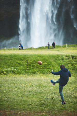 man playing the ball near famous Seljalandsfoss waterfall in southern Iceland. treking in Iceland. Travel and landscape photography conceptの写真素材