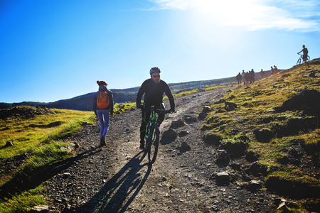 back view of woman traveler on a walk in the Valley of the river of Hveragerdi Iceland, the cyclist bikes down the slope. Hiking Tour of Reykjadalur Hot Springsの写真素材