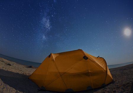 orange tent on the beach at night under the starry sky. Travel photography conceptの写真素材