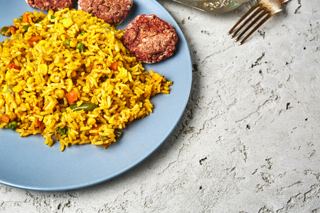 top view of a risotto with vegetables and vegan beet cutlets served on the blue dish on a gray concrete backdrop. vegan and vegeterian food cooking concept. kitchen layout, copy spaceの写真素材