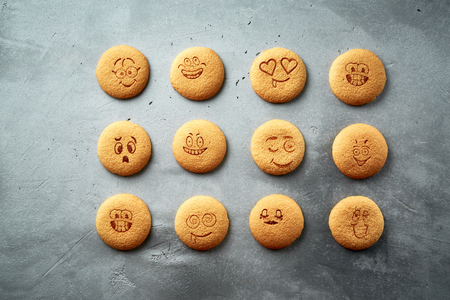 set of round cookies with different emotions, faces with emotions on a dark concrete backdropの写真素材