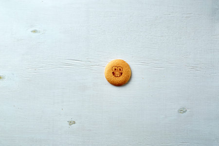 round cookie with cheerful emotion, face with emotion on a dark concrete backdropの写真素材