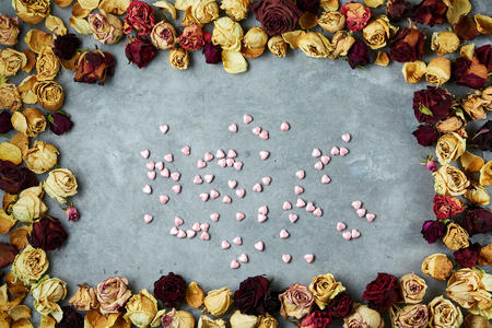 small decorative hearts in frame from dried roses buds on the gray concrete background. Valentines Day holiday concept, top view with copyspaceの写真素材
