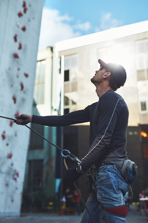 man climber belaying partner on the open climbing gym with rope using belaying deviceの写真素材